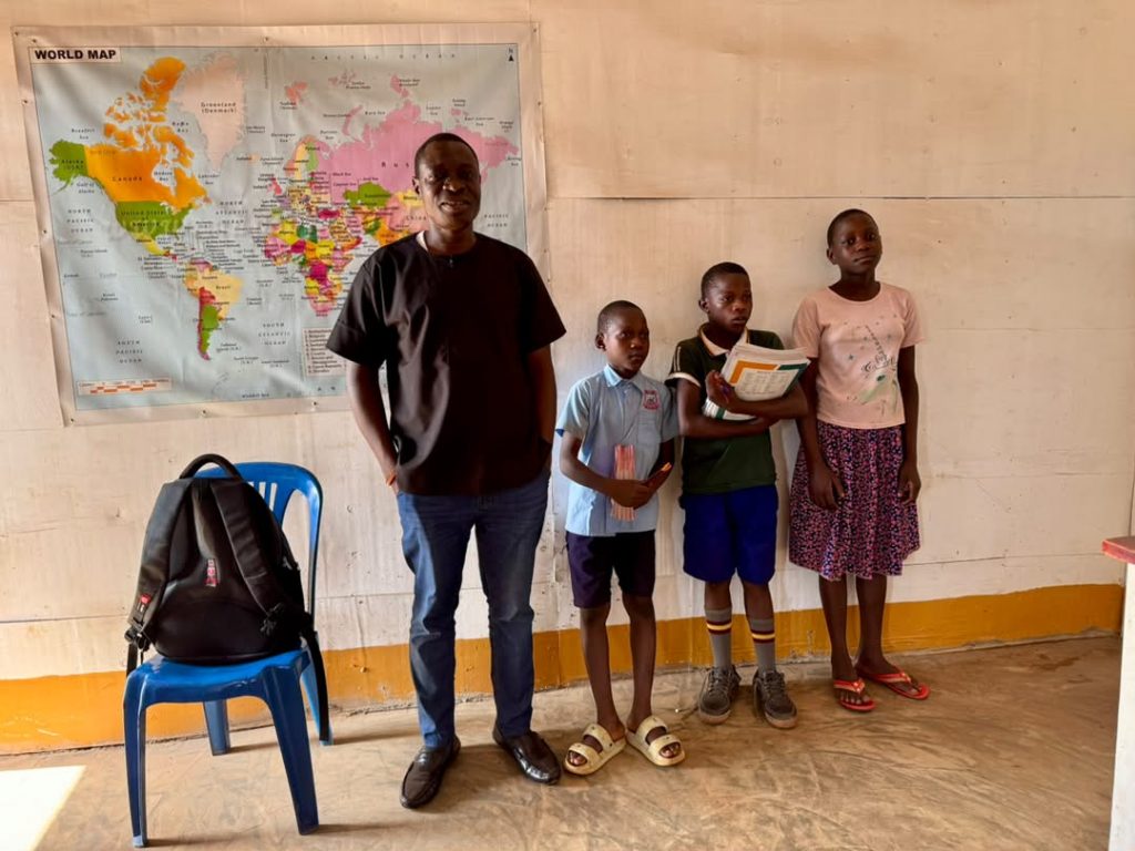 Ophelia Foundation representative standing with three students inside a classroom in Uganda