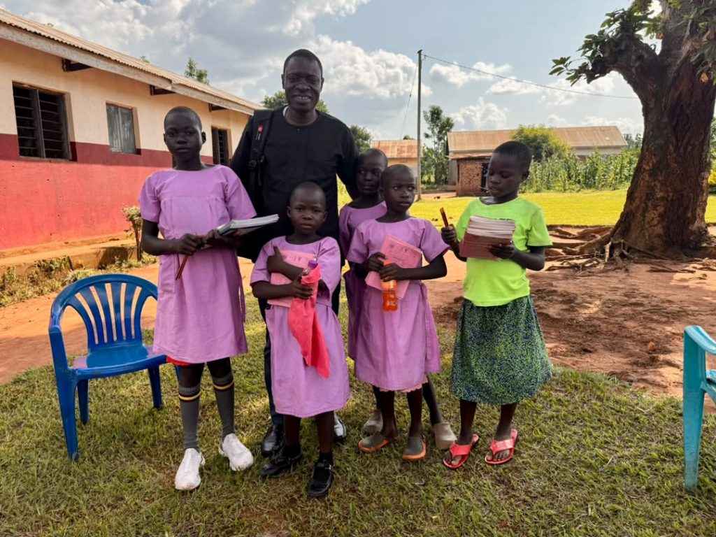 Foundation representative standing with students holding books and school supplies outdoors