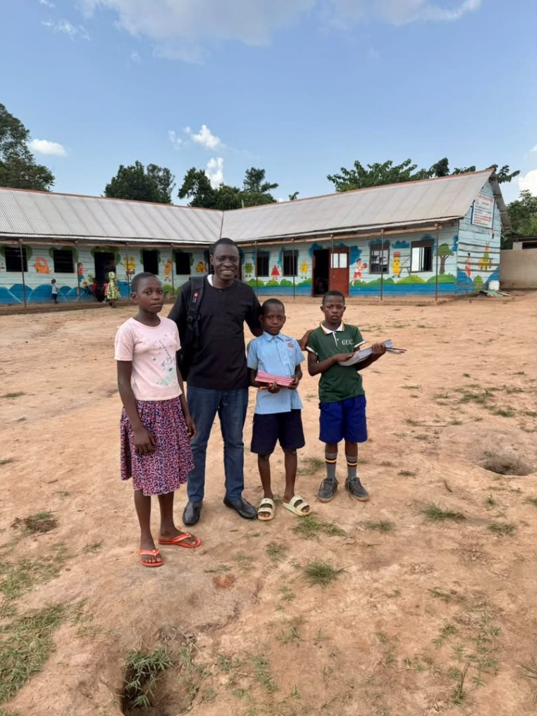 Foundation representative standing with three students outside a school building