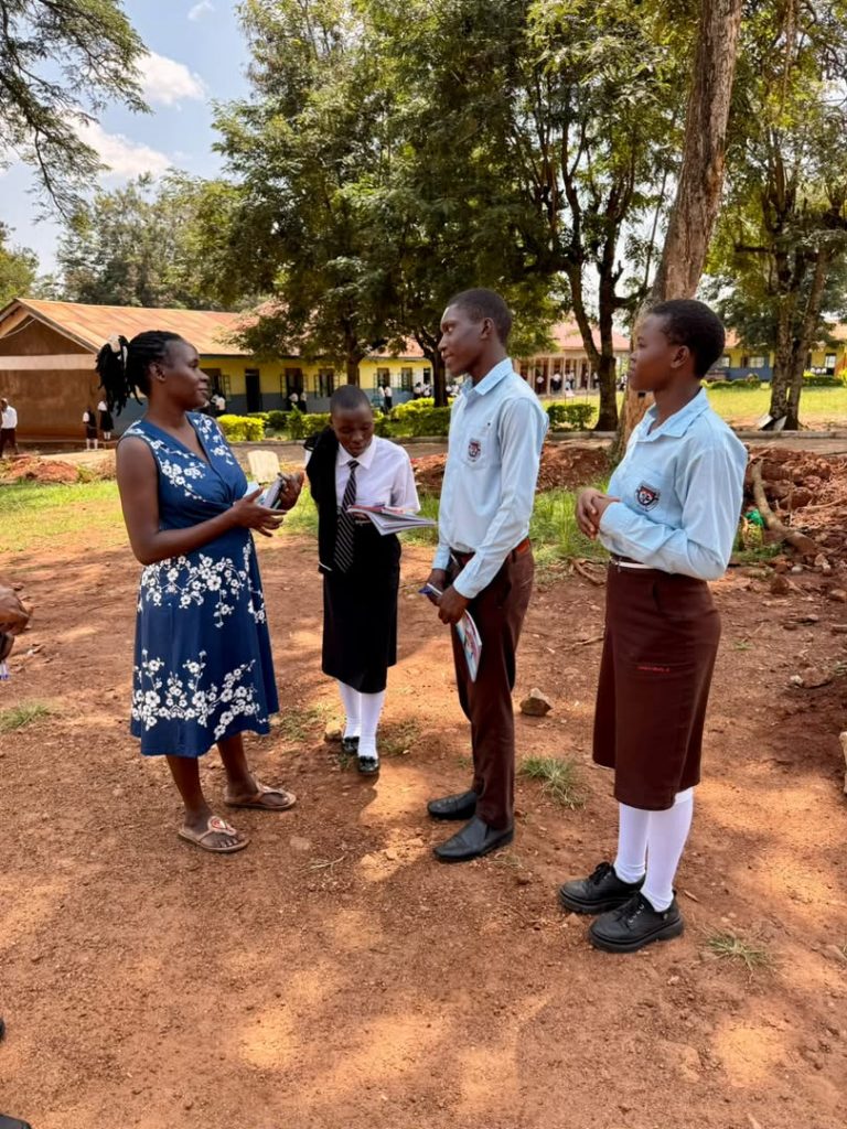 School staff member speaking with three students holding books on a school campus