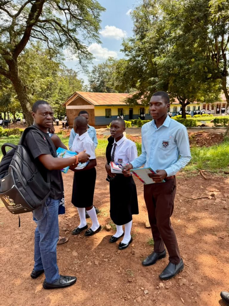 Foundation representative handing books and notebooks to students in school uniforms