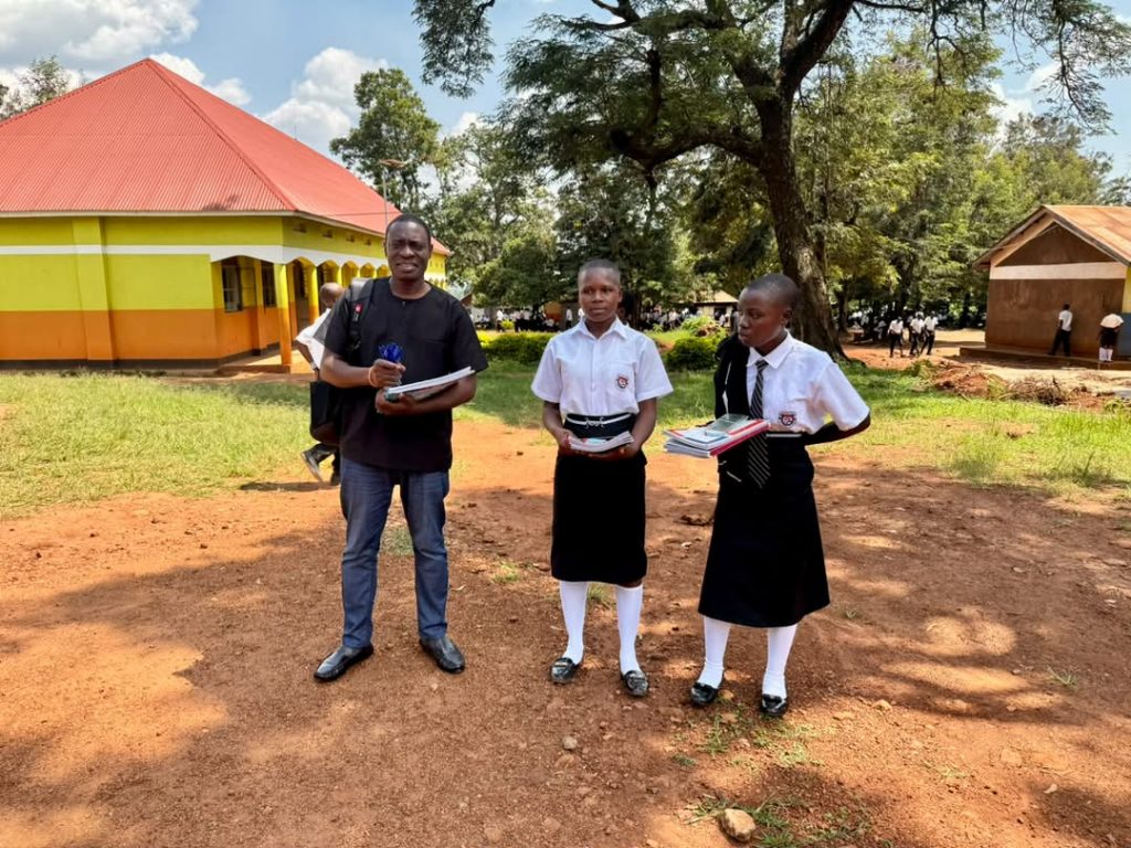 Foundation representative standing outside with two students holding books