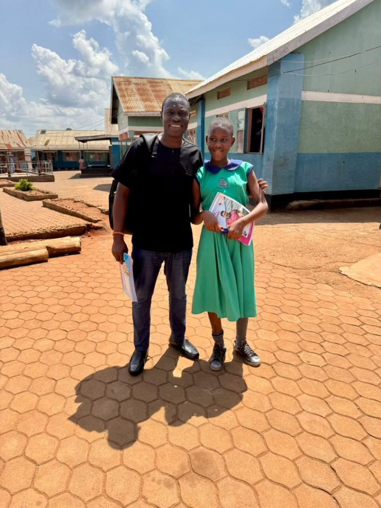 Foundation representative standing with a student holding books outside a school building