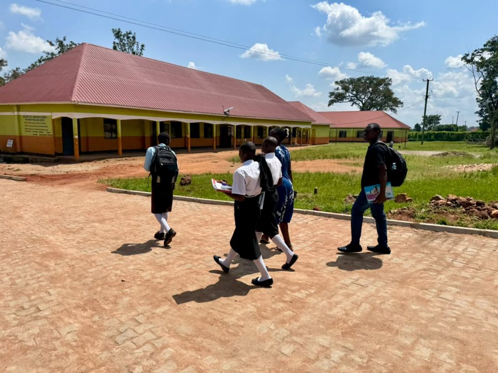 Foundation team and students walking across a school campus in Kamuli District