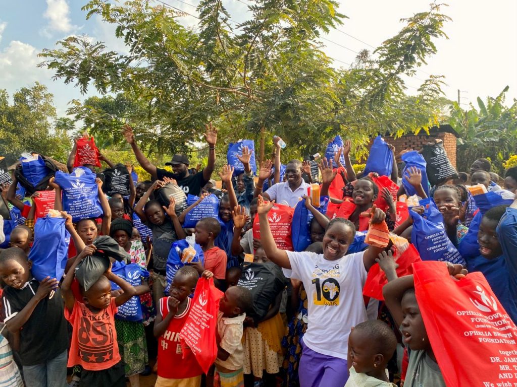 Group of children holding red, blue, and black Christmas packages outdoors