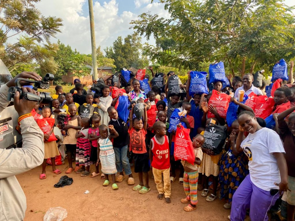 Large group of children displaying colorful food packages during the Christmas celebration