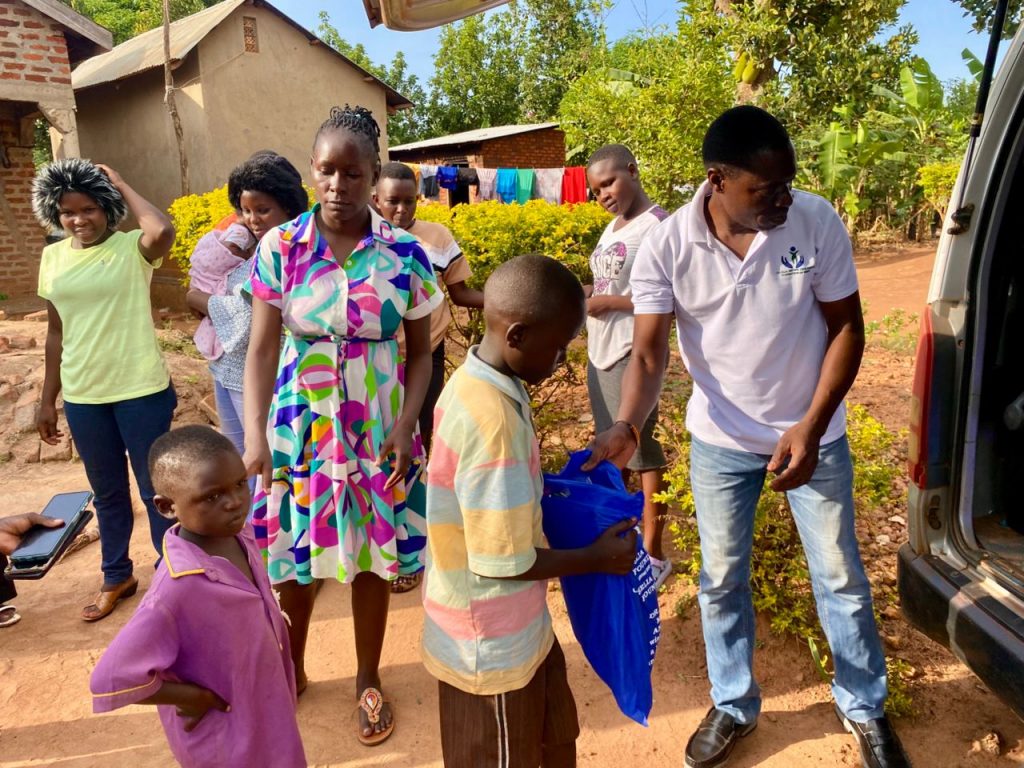 Boy receiving a blue Christmas package from Johns Brown beside the Foundation vehicle
