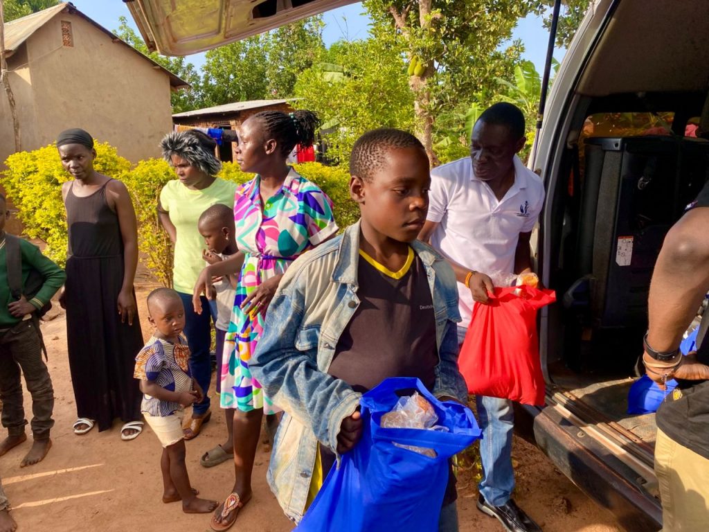 Child carrying a blue Christmas package beside the Foundation’s vehicle