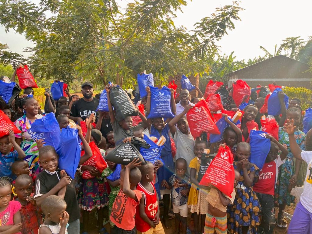 Large group of children and adults holding red, blue, and black Christmas packages