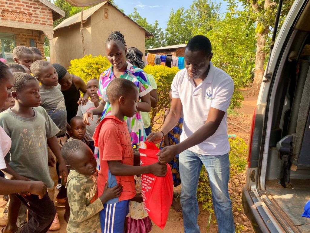 Johns Brown giving a red Christmas package to a boy beside the Foundation vehicle