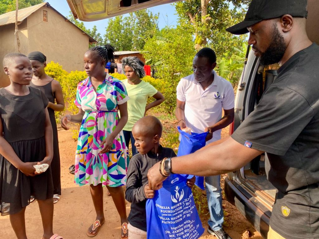 Girl receiving a blue Christmas package while Foundation volunteers assist